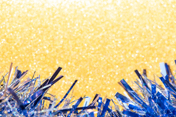 schönes blaues Lametta auf leuchtend gelbem Glitzerhintergrund für fes - Foto, Bild