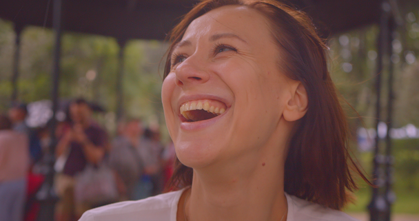 Close-up portret van jonge blanke vrouw kijken naar camera glimlachend vrolijk terwijl het regent in stedelijke stad buitenshuis - Video