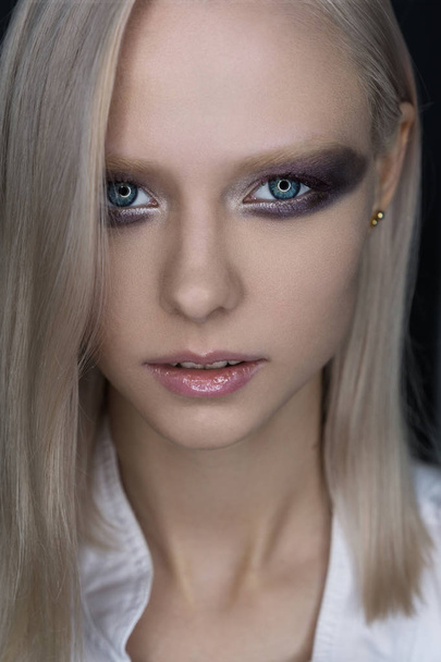 Close portrait of a platinum blue-eyed blonde with bright eye makeup in violet tones. - Foto, Imagen
