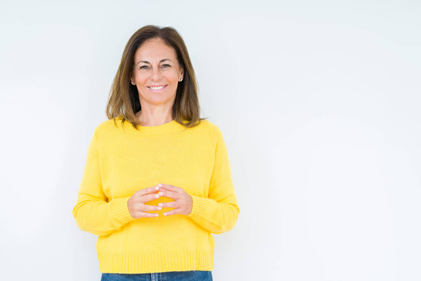 Mulher de meia-idade bonita vestindo suéter amarelo sobre fundo isolado Mãos juntas e dedos cruzados sorrindo relaxado e alegre. Sucesso e otimista
 - Foto, Imagem