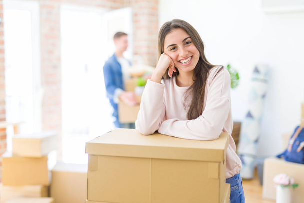 Beautiful young couple moving to a new home, young woman smiling happy to the camera excited for new apartment - Photo, Image