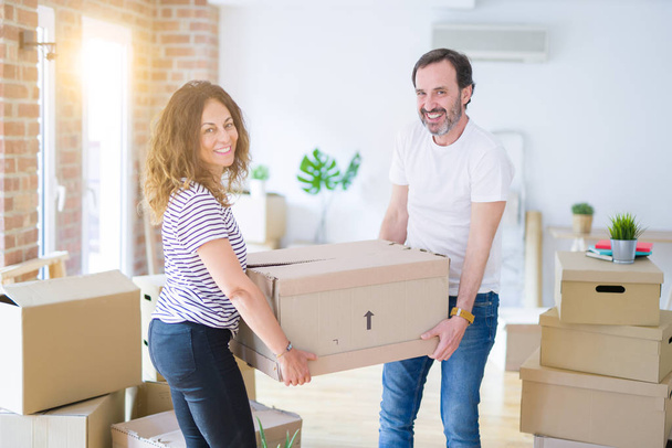 Middelbare leeftijd Senior paar verhuizen naar een nieuw huis, holding kartonnen boksen glimlachen gelukkig verliefd op apartmant - Foto, afbeelding
