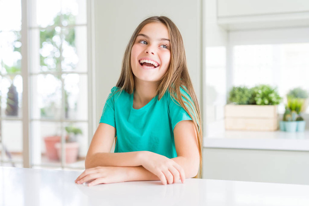 Piękna młoda dziewczyna dziecko nosi zielone t-shirt patrząc z dala do boku z uśmiechem na twarzy, naturalny wyraz. Śmiać się pewnie. - Zdjęcie, obraz
