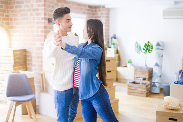 Young asian couple dancing and smiling celebrating moving to a new home - Фото, изображение