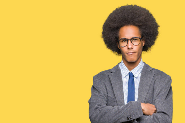 Young african american business man with afro hair wearing glasses skeptic and nervous, disapproving expression on face with crossed arms. Negative person. - Photo, Image