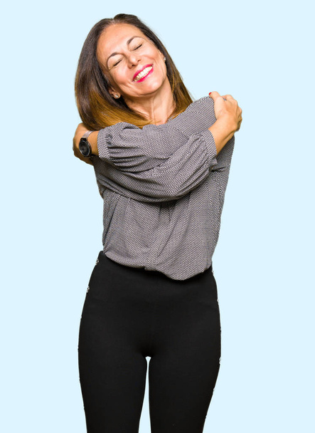 Красивая деловая женщина средних лет обнимает себя счастливой и позитивной, уверенно улыбаясь. Самолюбие и забота о себе
 - Фото, изображение