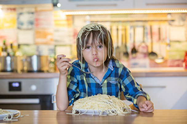 Little preschool boy, cute child, eating spaghetti for lunch and - Foto, afbeelding