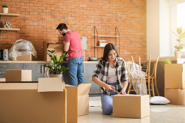 Young couple unpacking things after moving into new house - Photo, Image