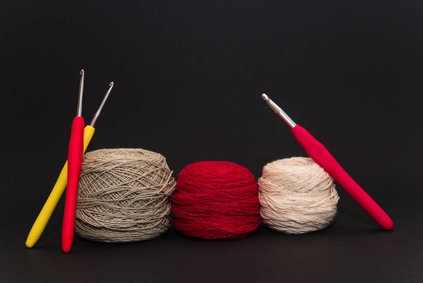 colored balls of thread and crochet hooks on a black background space for text - Foto, Bild