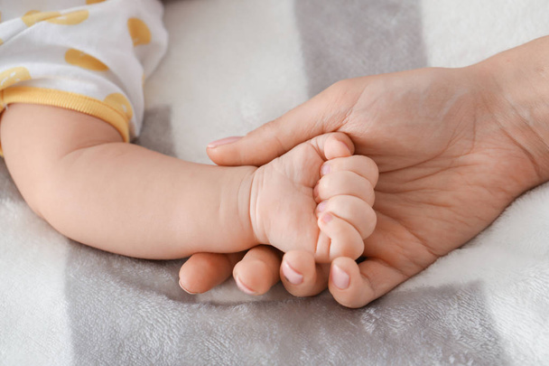 Hands of mother and cute little baby lying on bed, closeup - Valokuva, kuva