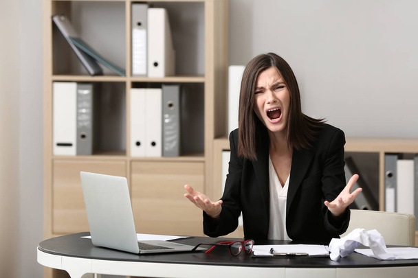 Mujer joven estresada en el lugar de trabajo en la oficina
 - Foto, imagen