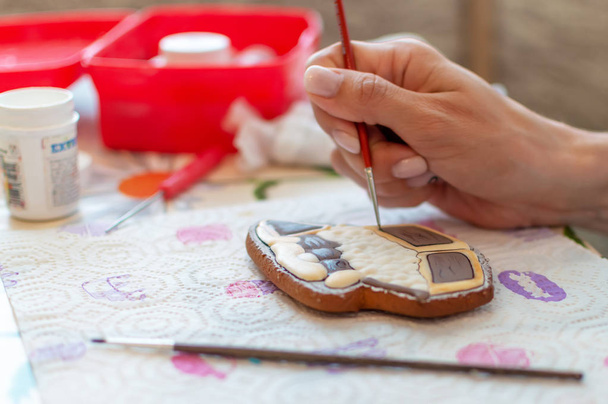 Close-up of confectioner's hands painting with brush on gingerbread - Foto, afbeelding