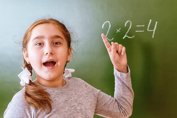 Schoolgirl solves a math problem on the blackboard during the lesson. - Photo, Image
