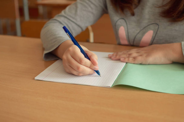 hand of a teenage girl writes with a ballpoint pen in a terad during a lesson at school - 写真・画像