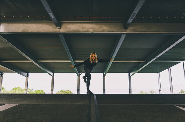 Beautiful blonde caucasian young woman standing in garage on one - Photo, image