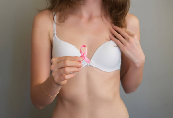 女性の胸にピンクのリボンクローズアップ,乳がん,10月の意識月医療・ヘルスケアの概念.  - 写真・画像