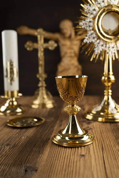 Catholic concept background. The Cross, monstrance, Jesus figure, Holy Bible and golden chalice on the altar. - Photo, Image