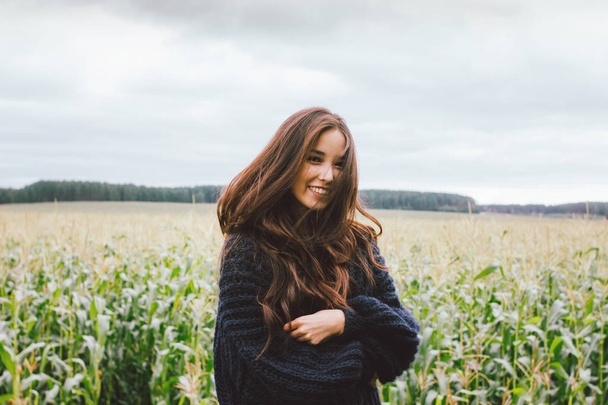 Beautiful carefree long hair asian girl in knitted sweater in autumn corn field. Sensitivity to nature concept - Foto, afbeelding