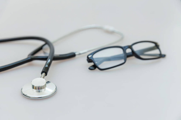 Medicine berendezések sztetoszkóp vagy fonendoszkóp és szemüveg izolált fehér háttér. A készülék az orvos. Egészségügyi életbiztosítási koncepció - Fotó, kép