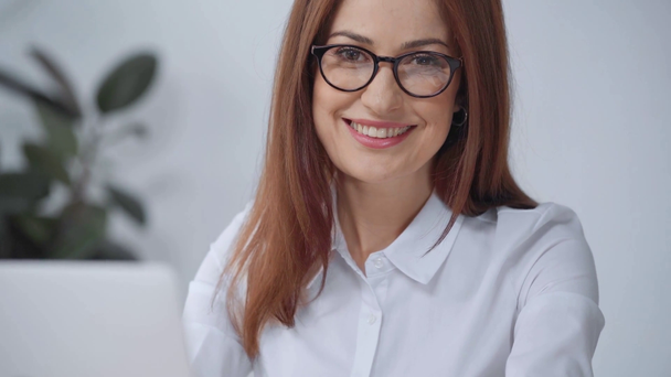 uśmiechnięta businesswoman w okularach patrząc na kamerę - Materiał filmowy, wideo