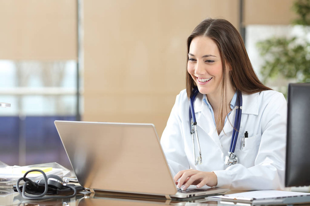 Happy doctor using a laptop at consultation - Foto, imagen