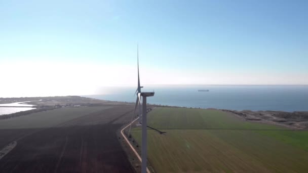 Группа белых ветряных энергетических башен строит мельницы в поле у моря. Зеленая, чистая, возобновляемая энергия. Съёмки с воздуха
. - Кадры, видео