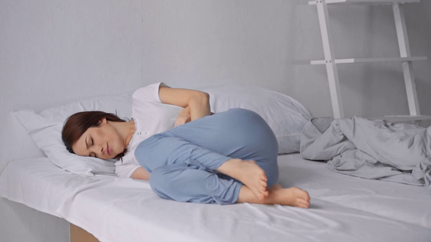 γυναίκα που κείτεται στο κρεβάτι και υποφέρει από πόνο στο στομάχι - Πλάνα, βίντεο