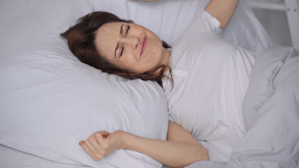 γυναίκα ξαπλωμένο στο κρεβάτι και υποφέρει από θόρυβο - Πλάνα, βίντεο