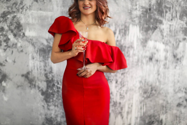 Smiling woman in red dress with a glass of champagne. Party conc - 写真・画像