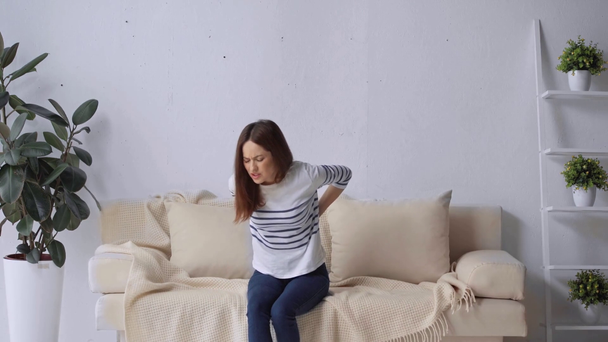 woman suffering from backache in living room - Filmagem, Vídeo