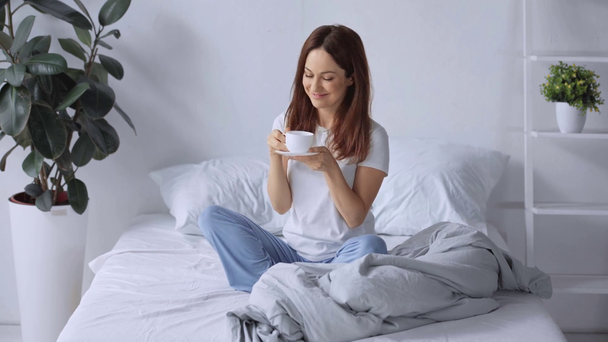 Gelukkige vrouw die koffie drinkt in bed in de ochtend - Video