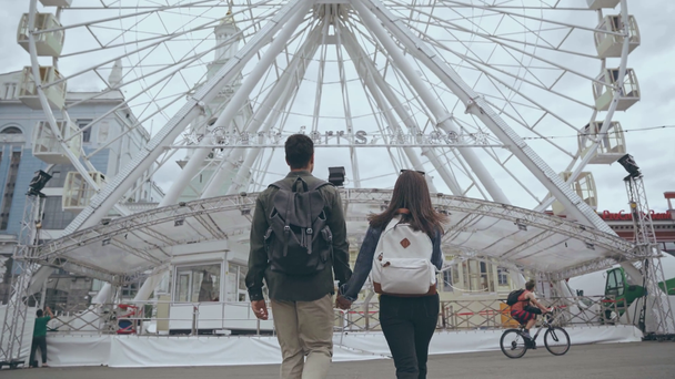 KYIV, UKRAINE - JULY 9, 2019: back view of couple walking to Ferris wheel - Materiaali, video