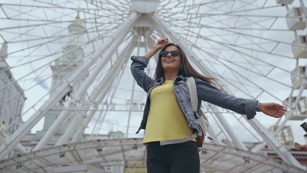 KYIV, UKRAINE - JULY 9, 2019: woman with backpack spinning near Ferris wheel - Filmmaterial, Video