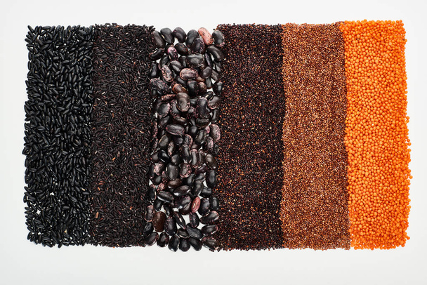pohled na rozmanité černé fazole, rýži, quinoa, pohanku a čočku izolované na bílém - Fotografie, Obrázek