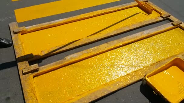 Reparatur eines Fußgängerüberwegs auf der Autobahn, der Mitarbeiter streicht mit einer Walze gelbe Linien auf die Straße - Filmmaterial, Video
