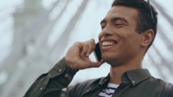 BI-rasowy człowiek śmieje się i rozmawia na smartfonie - Materiał filmowy, wideo