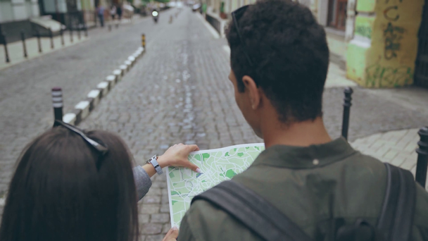 zurück Ansicht des Paares mit Karte, das auf der Straße geht - Filmmaterial, Video