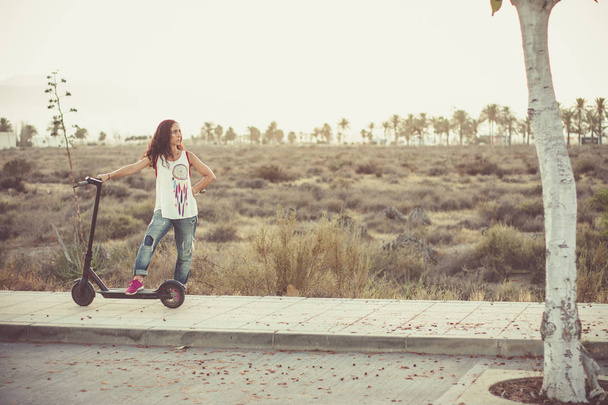 Женщина рядом со своим скутером с полупустынным пейзажем на заднем плане
 - Фото, изображение