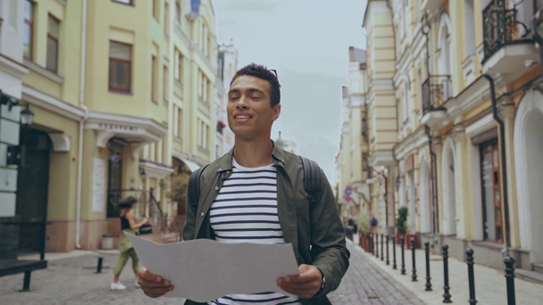 Zwei-Rassen-Mann läuft mit Karte auf Straße - Filmmaterial, Video