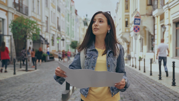 young woman walking on street with map - Filmati, video