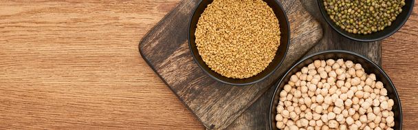 panoramic shot of bowls with grains and diverse legumes on wooden cutting boards - Photo, Image