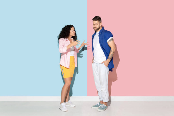 Young emotional man and woman on pink and blue background - 写真・画像