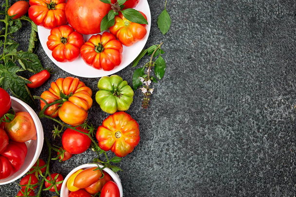 Mistura de fundo de tomates. Belos tomates vermelhos orgânicos suculentos no fundo da mesa preta. Conceito de comida limpa. Espaço de cópia, flat lay
 - Foto, Imagem
