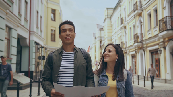 Interracial paar wandelen langs straat met kaart - Video