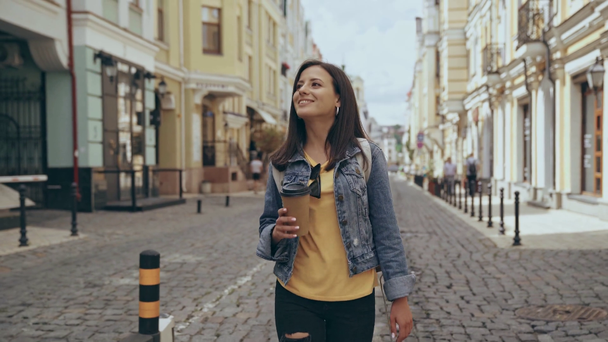 young woman walking and drinking coffee - Materiał filmowy, wideo