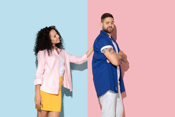 Young emotional man and woman on pink and blue background - Zdjęcie, obraz