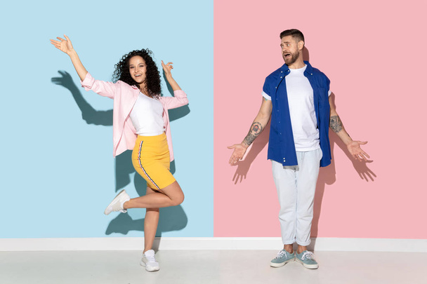 Young emotional man and woman on pink and blue background - Fotoğraf, Görsel