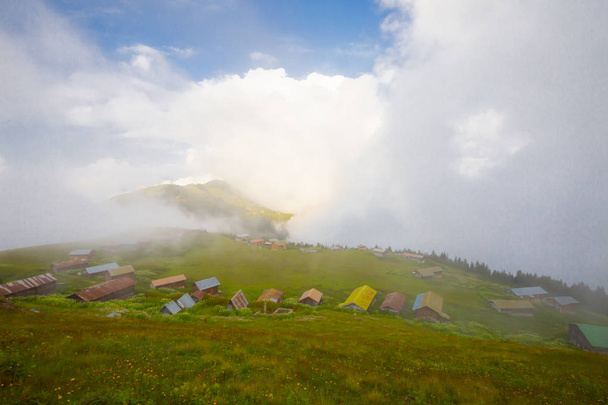 Green nature, snowy mountains and traditional wooden plateau houses (yayla evi) of northeastern Karadeniz region of Turkey. Landscape shot was taken in June 2019 at Pokut Plateau, Rize. - Photo, Image