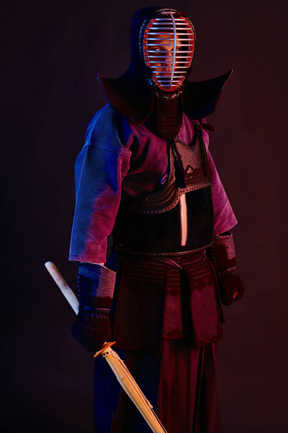 Lähikuva ammuttu, Kendo taistelija yllään haarniska, perinteinen kimono, kypärä harjoitellaan kamppailulaji shinai bambu miekka, musta tausta
. - Valokuva, kuva