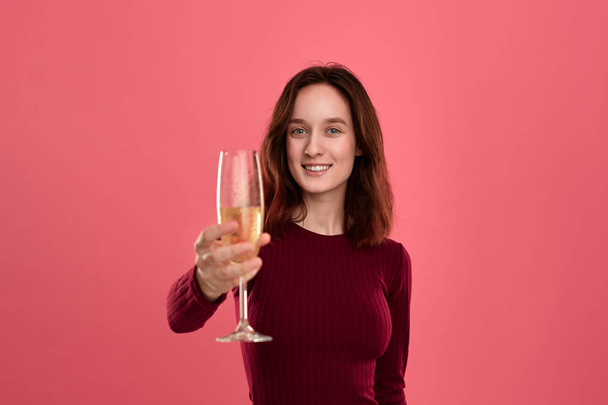 Menina bonita morena animado segurando vinho de champanhe espumante de pé isolado em um fundo rosa escuro e sorrindo para a câmera. Conceito de celebração
 - Foto, Imagem